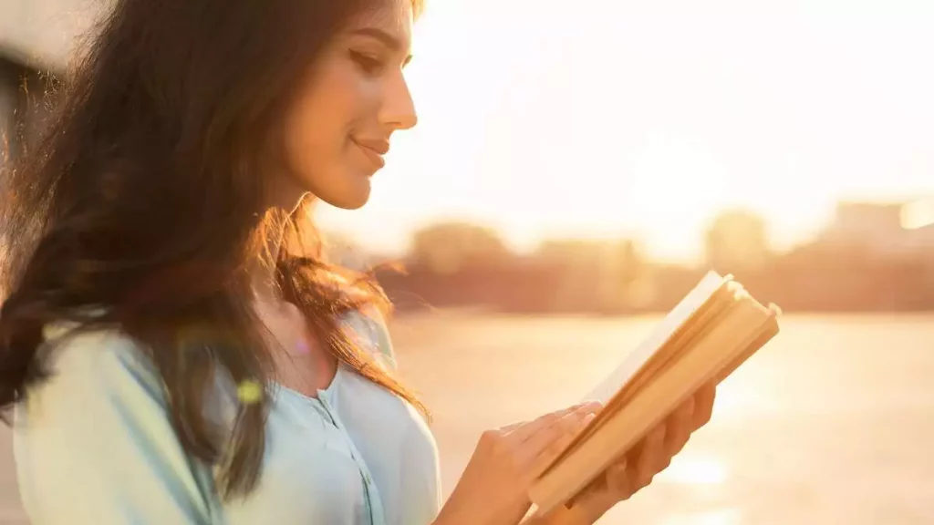 Woman holding the booking reading it while walking outdoors