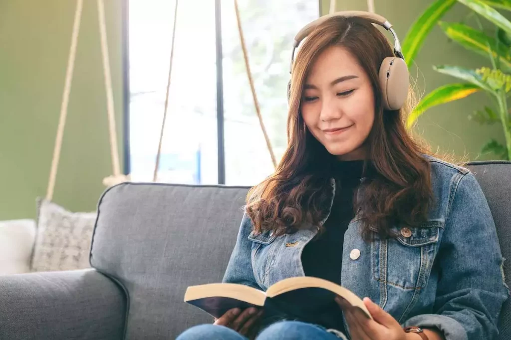 A beautiful asian woman reading book and listening to music with headphones