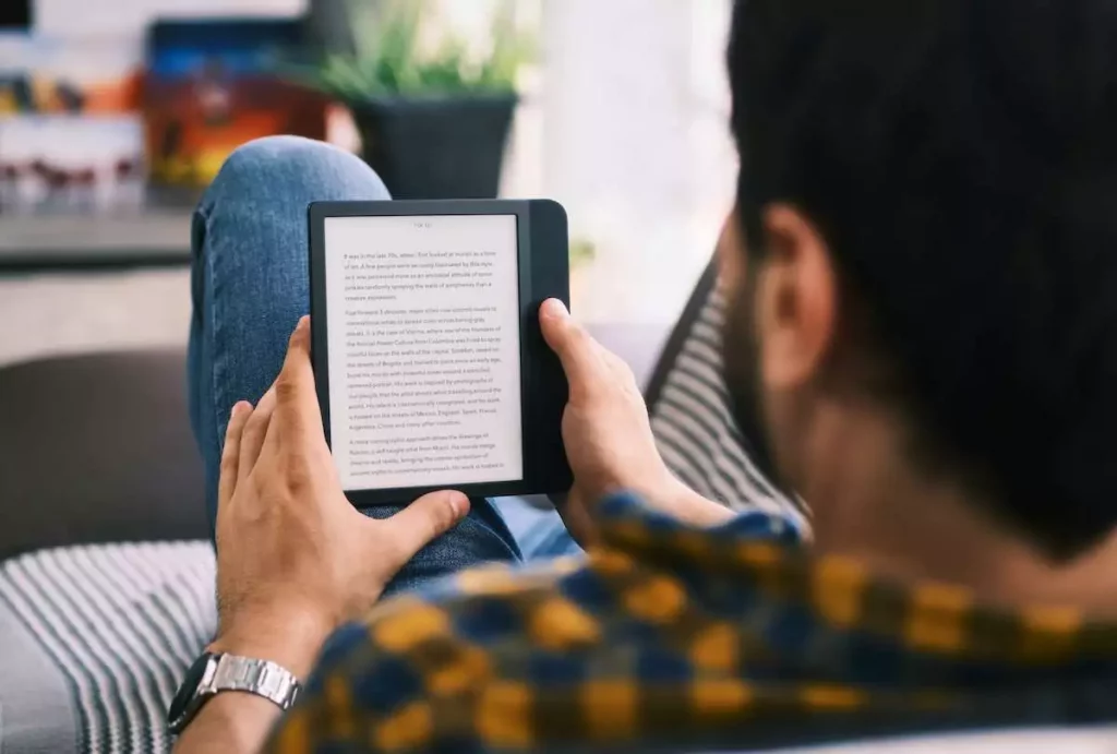 Young man reading ebook using ereader on couch