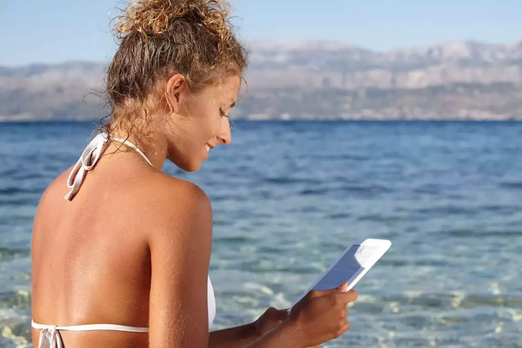 woman reading on a kindle on a beach