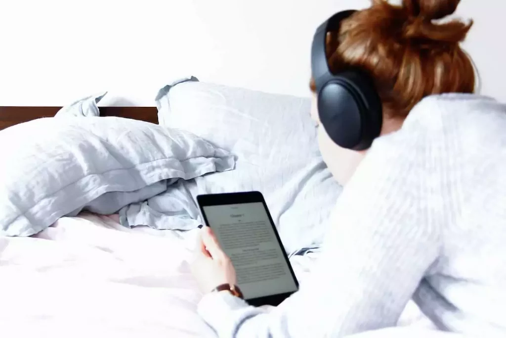 woman reading a kindle on bed